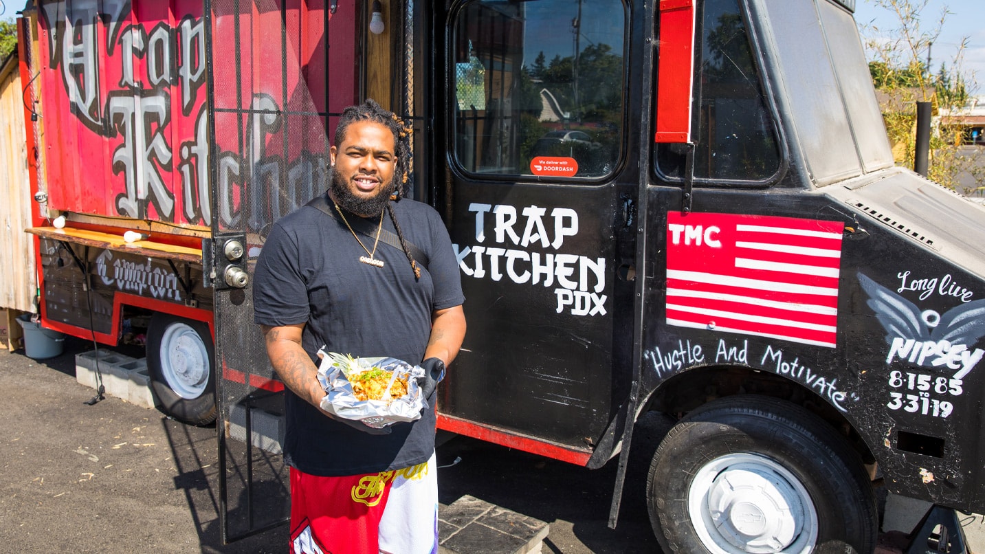 The owner of a food truck holds a plate of food