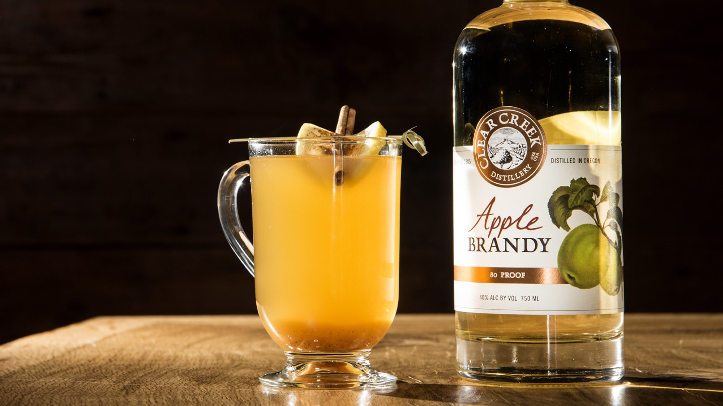 A bottle of apple brandy sits next to a hot toddy