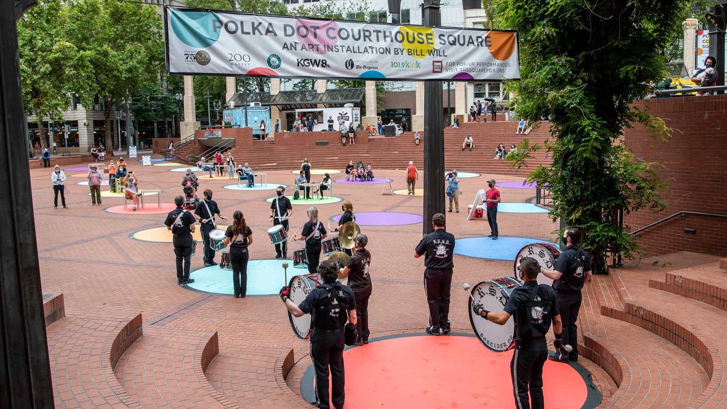 A band plays on colorfully painted circles in a public square