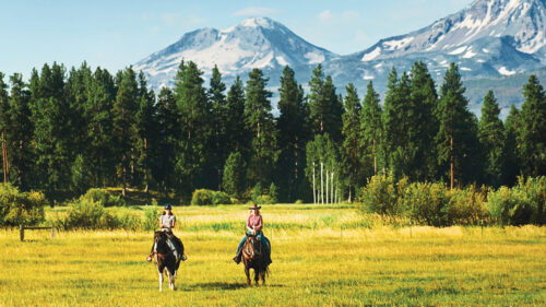 Horseback riders with snow-capped mountains in the distance