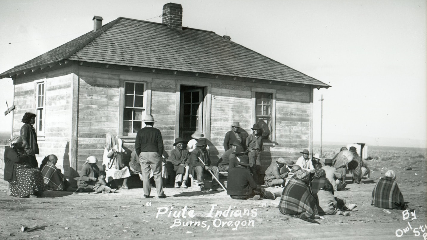 People sit and stand outside of an old building