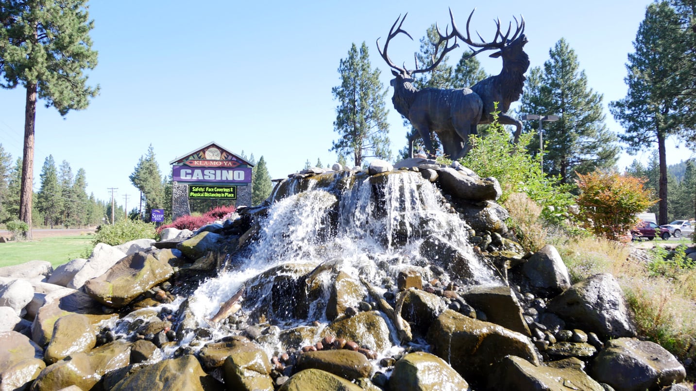 A bronze elk statue on a fountain in front of a casino sign