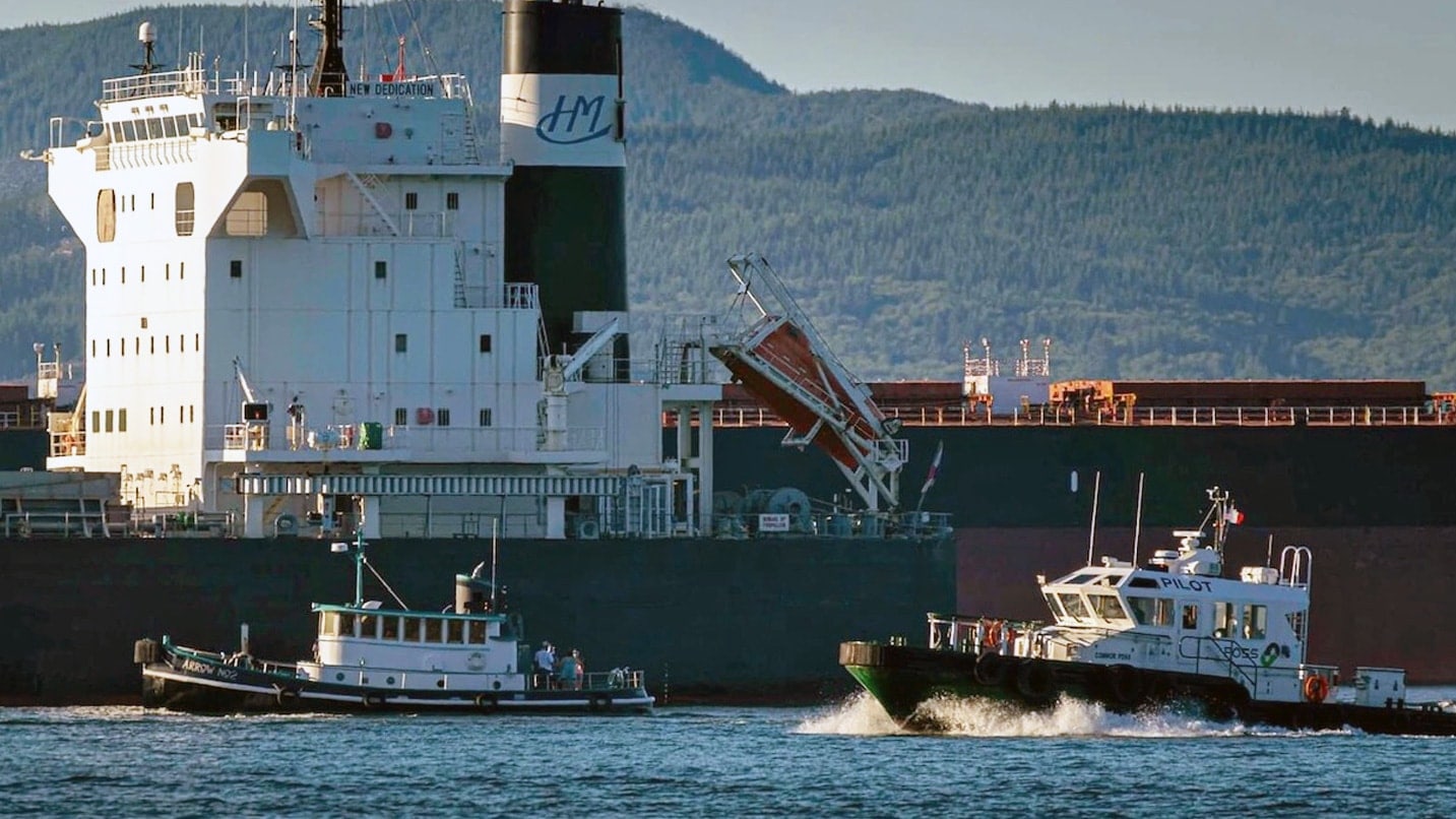 A tugboat pulls alongside a ship and pilot boat