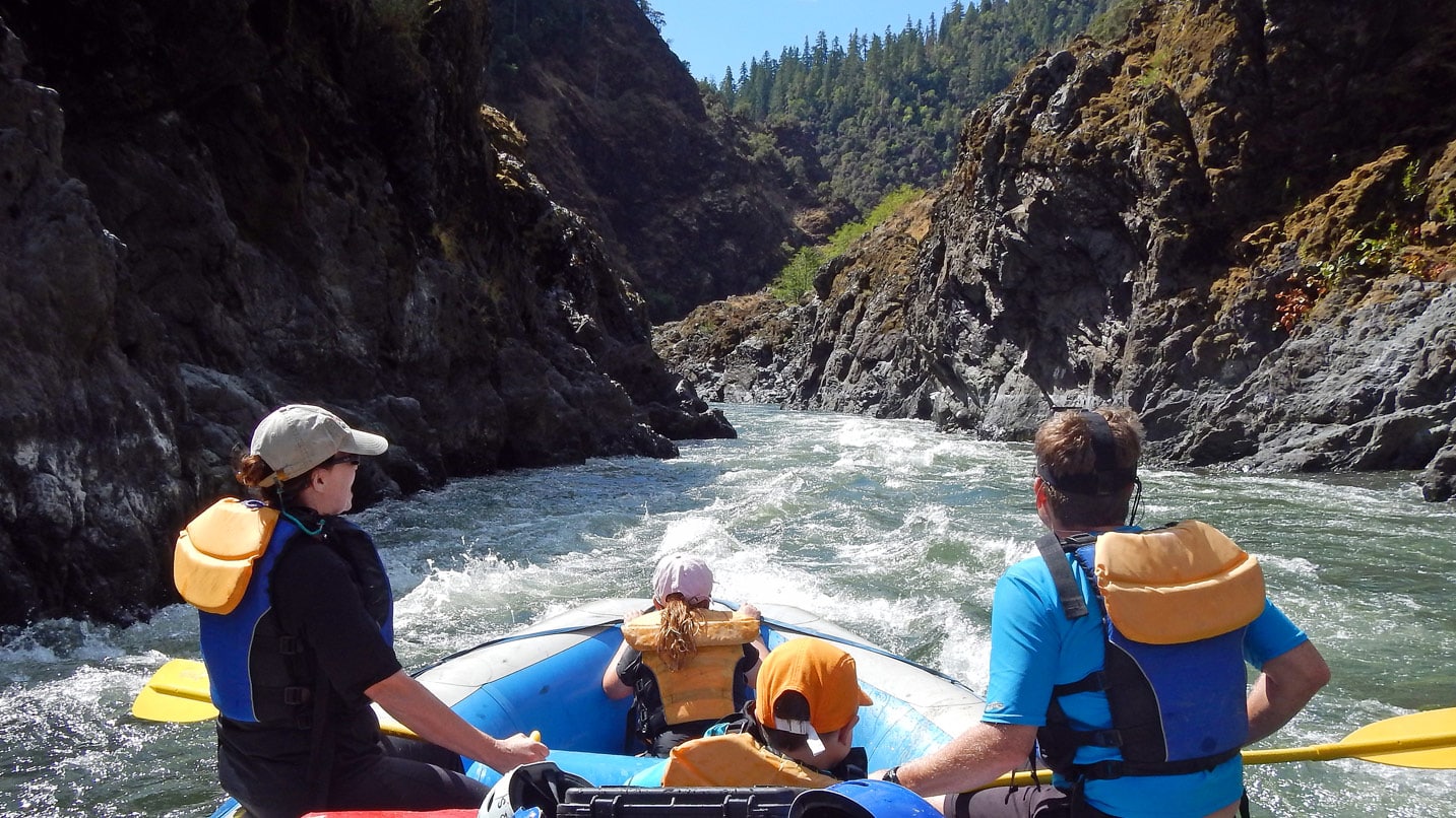 A man, woman and child raft down a river canyon