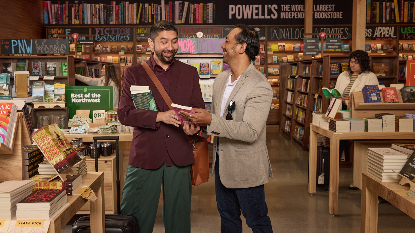 Two men exchange a book at the Powell's stand inside the Portland airport.