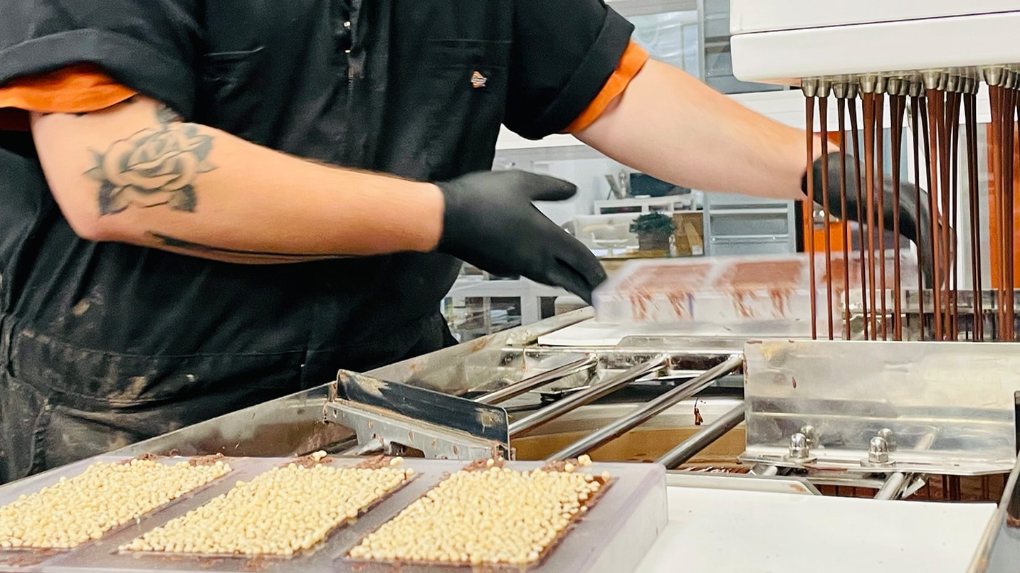 A person wears gloves while working with chocolate