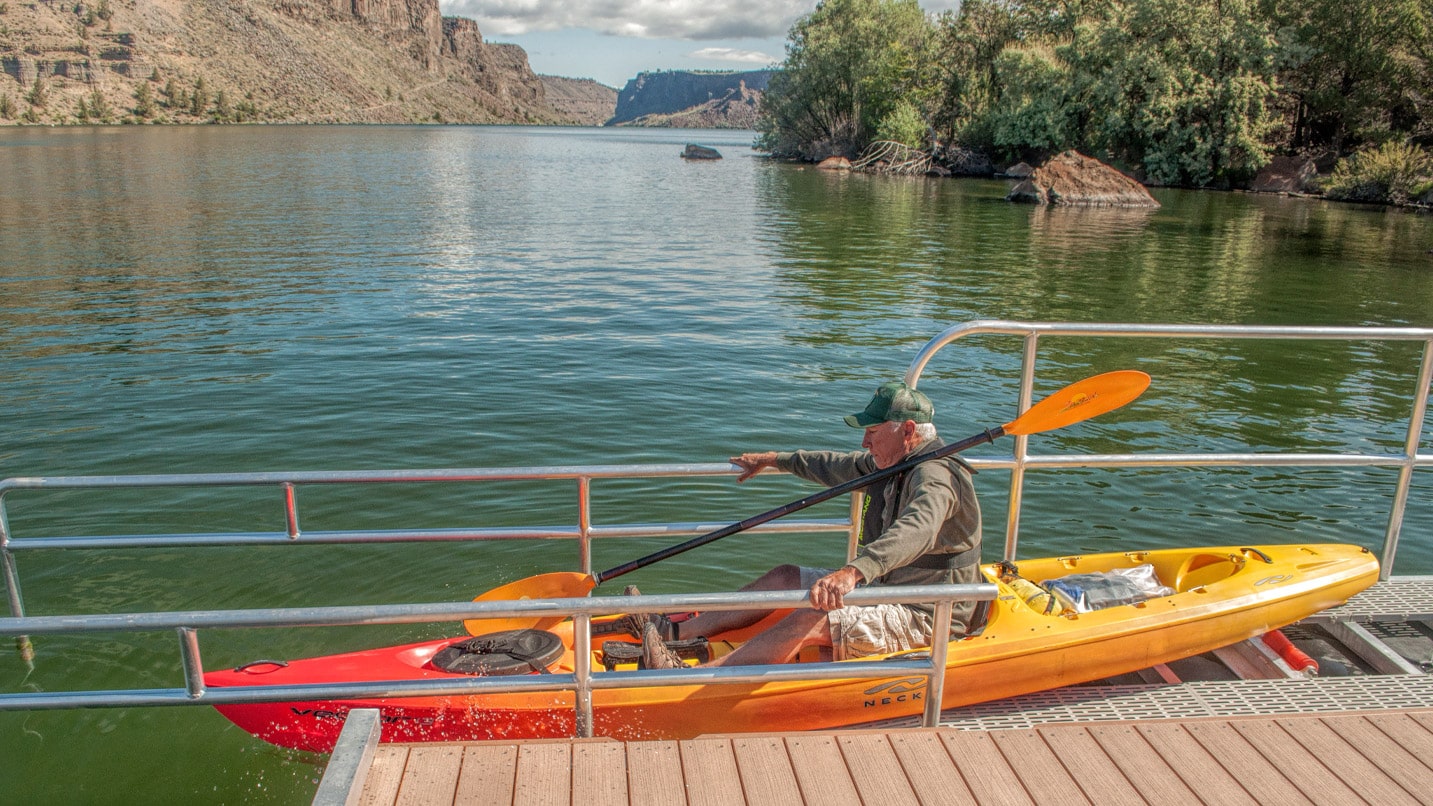 man sits in kayak on dock in lake