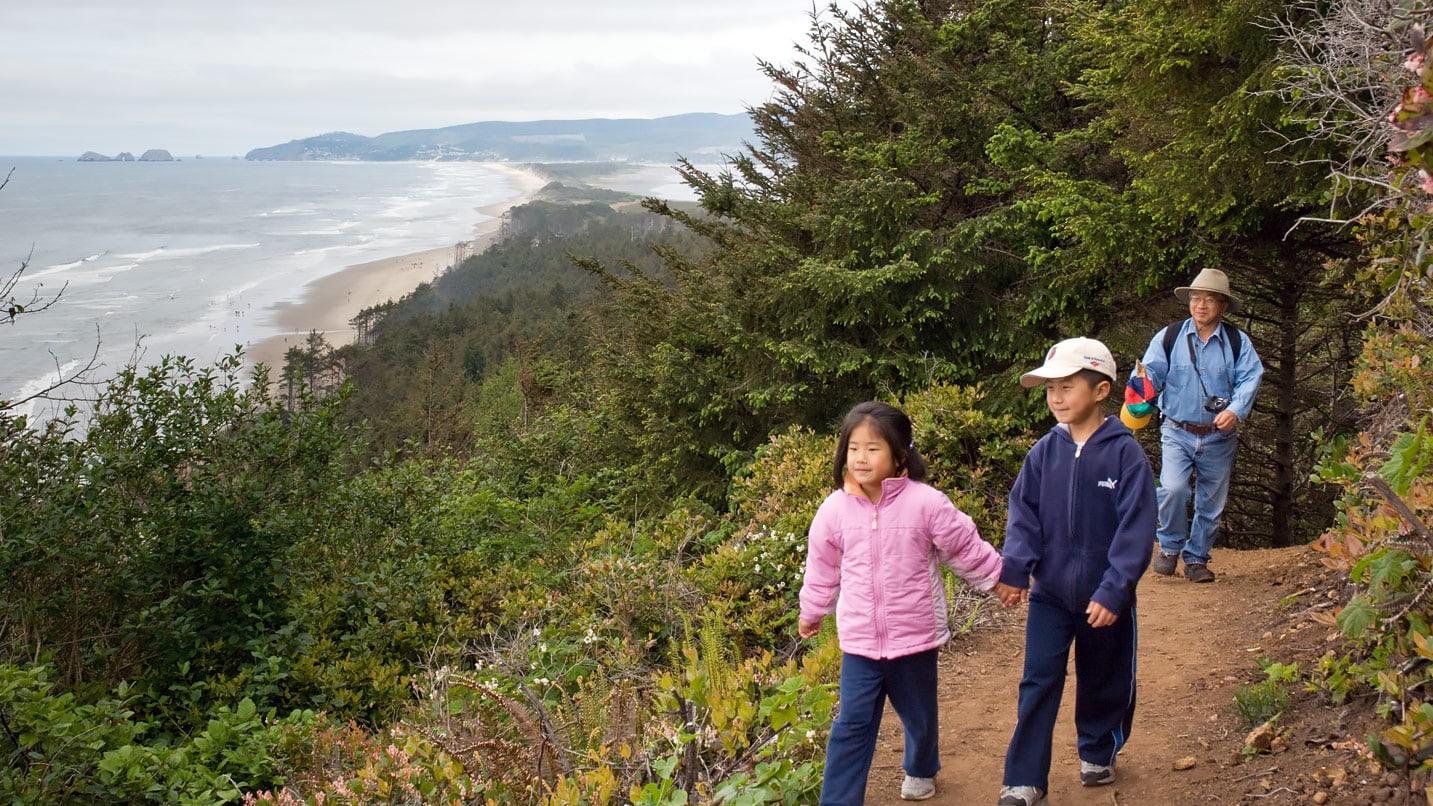 Kids hold hands on a trail next to the ocean