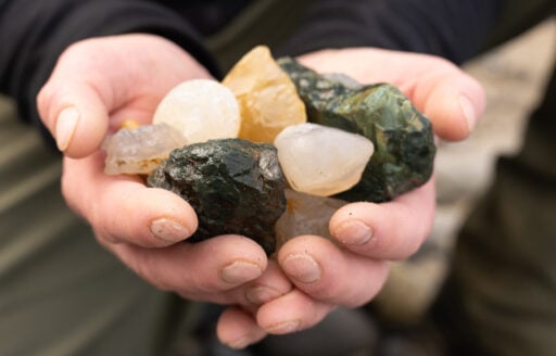 Hands hold a collection of shiny colorful rocks