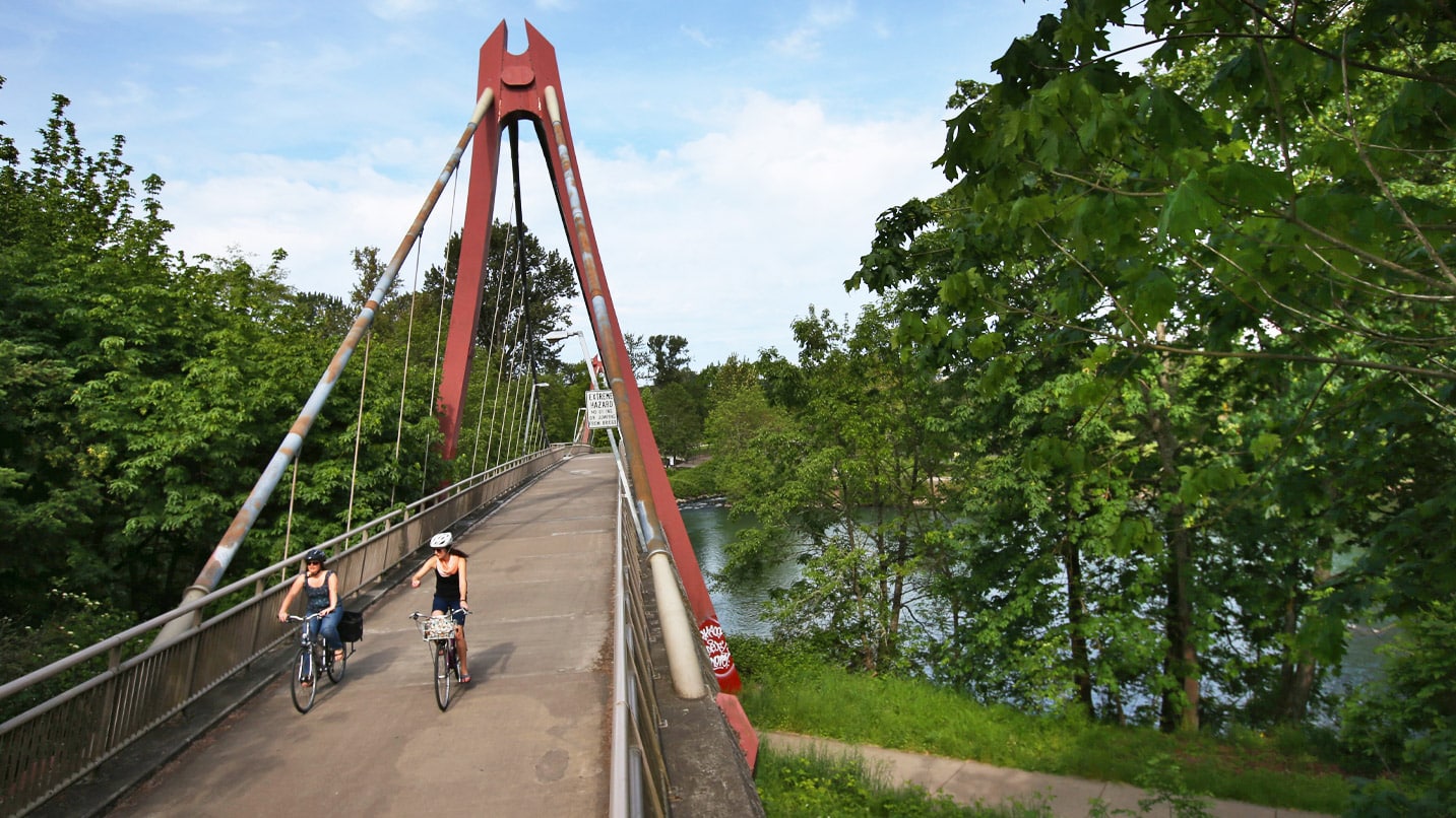Two cyclists ride over a pedestrian bridge