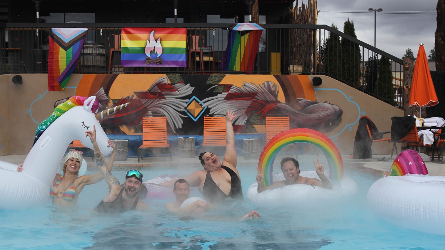 people in hot tub with colorful signs