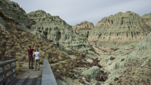 People walking over a metal bridge in a stone valley