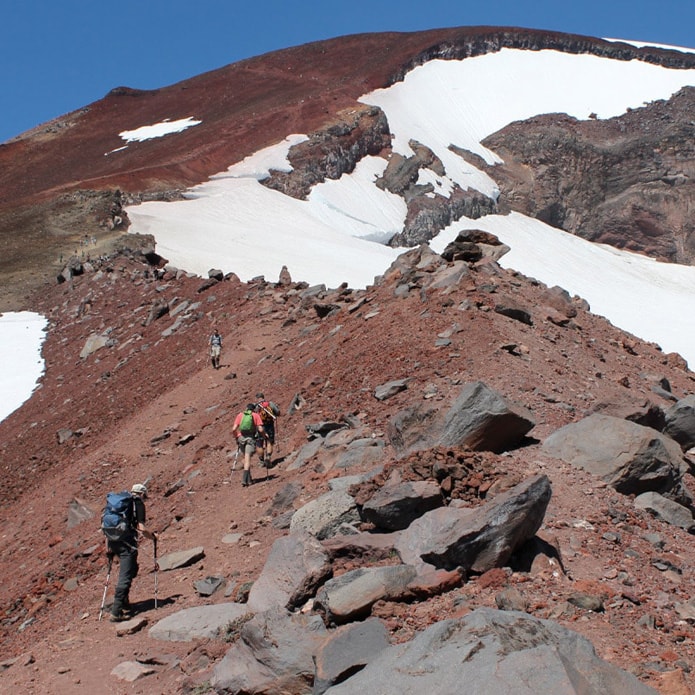 hikers summit south sister mountain with lingering snow
