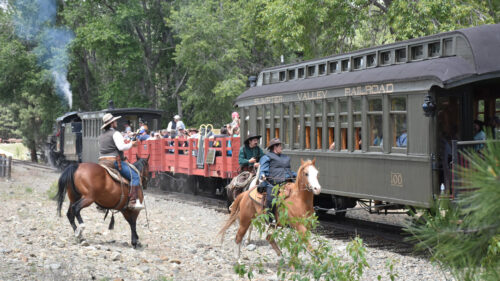 Horseback riders alongside a passenger train