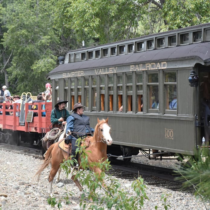 sumpter train with passengers with people on horseback