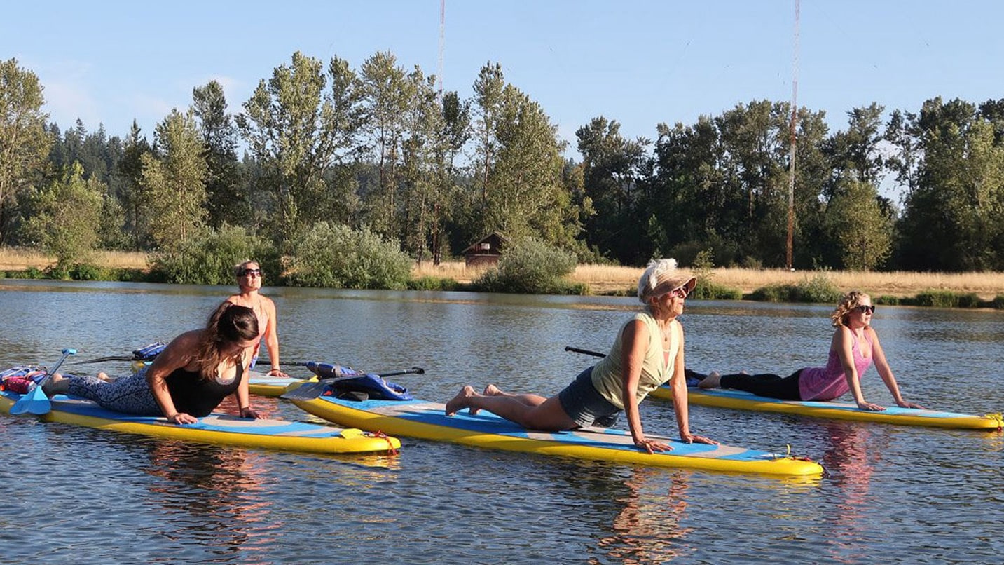 people do yoga on floating paddleboards