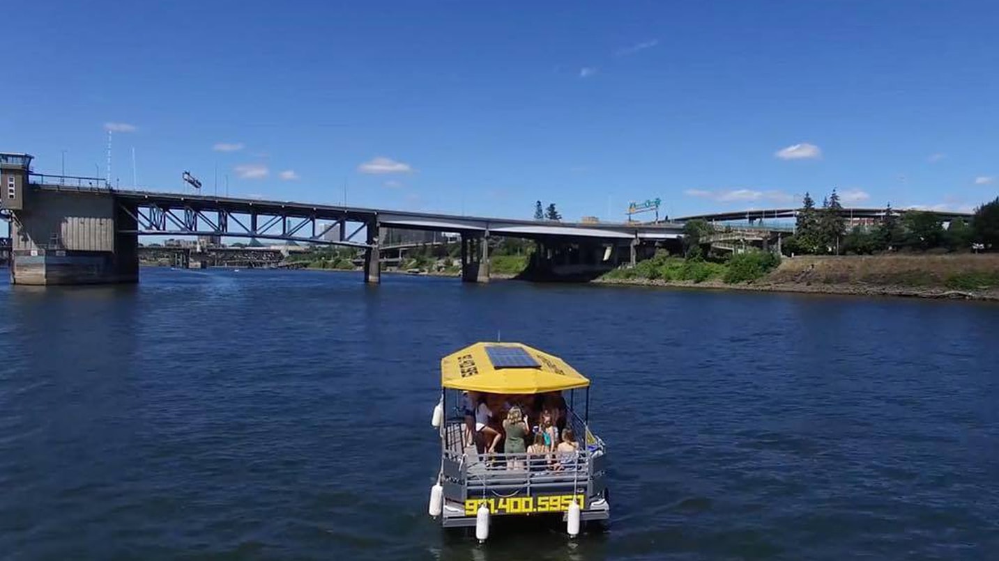 yellow boat with people on river with bridge in background