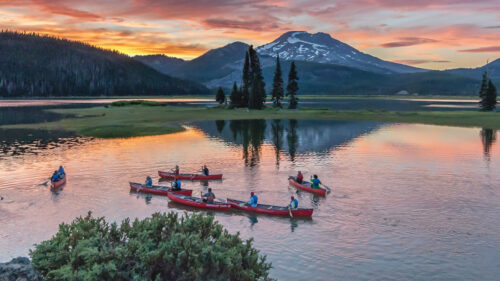 kayakers on water against sunset and mountain