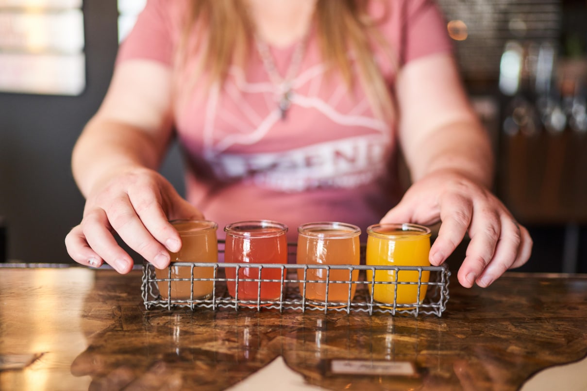 woman holds small glasses of colorful cider