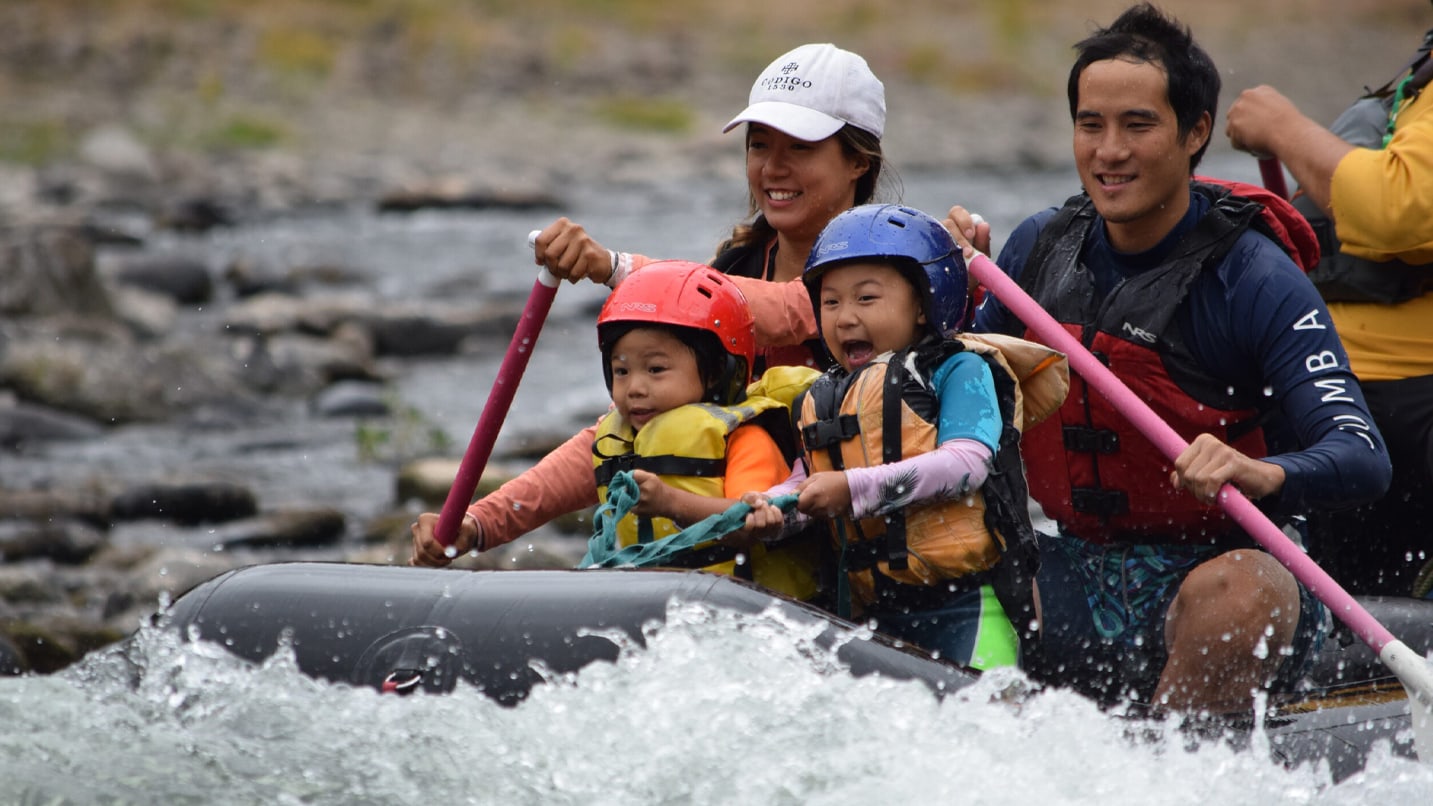 two children and two adults paddle raft