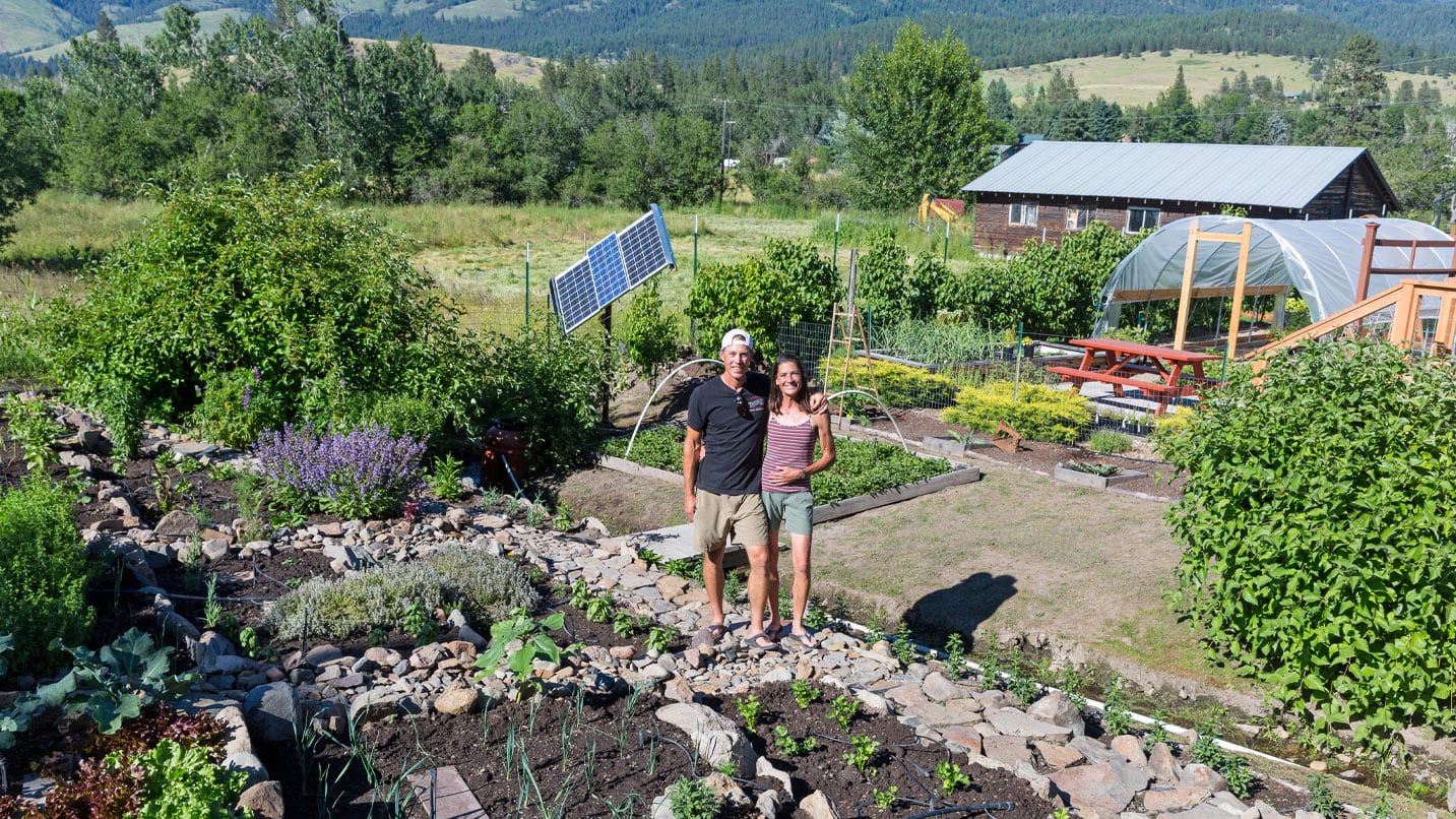 Two people stand in a small farm looking at the camera