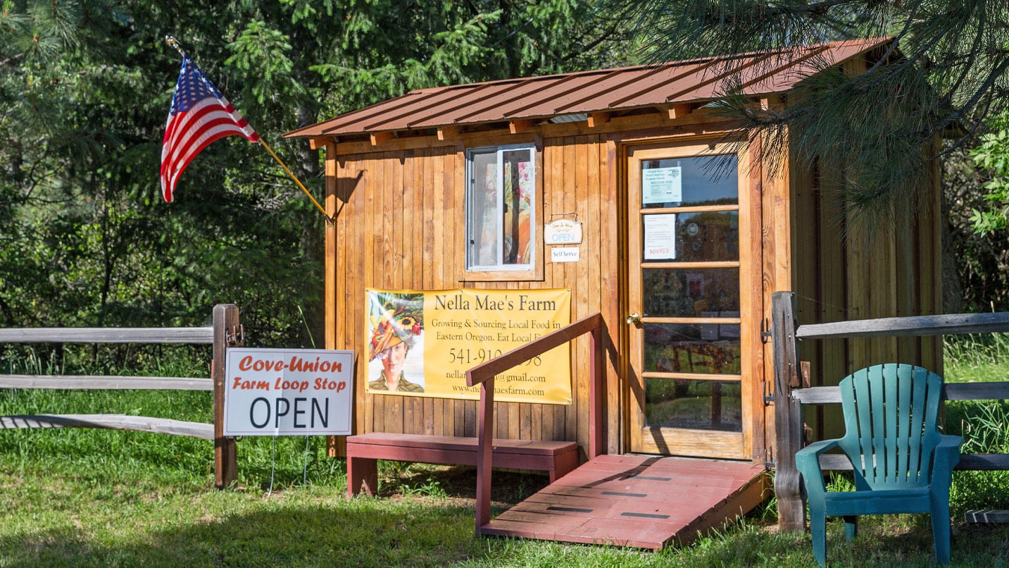 A small wooded farm stand with an open sign