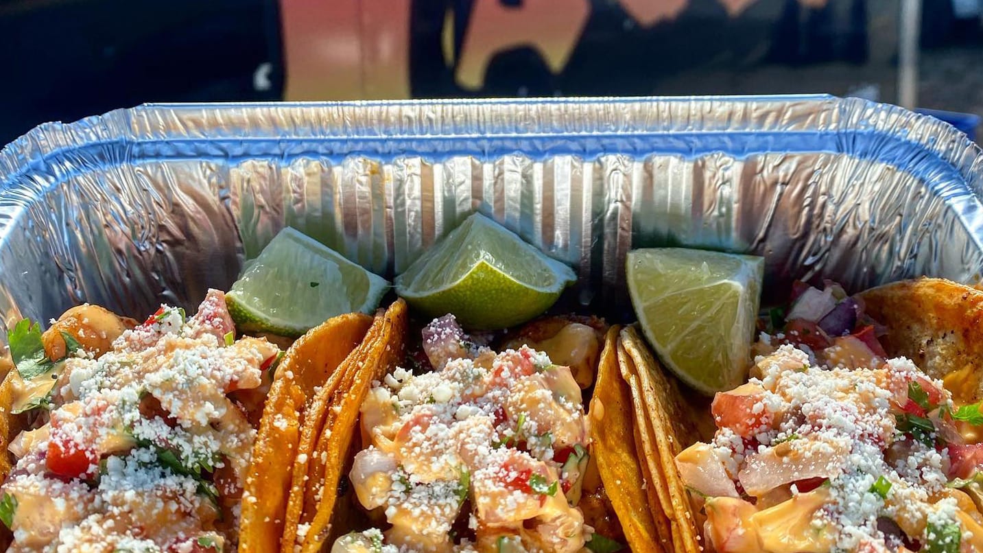 crispy taco shells with fillings and lime wedges in aluminum tray