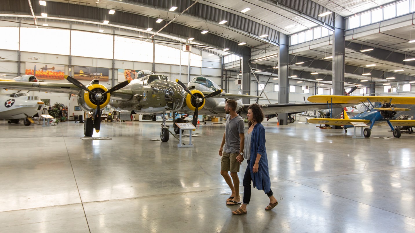 two people walk in airplane hangar near small planes