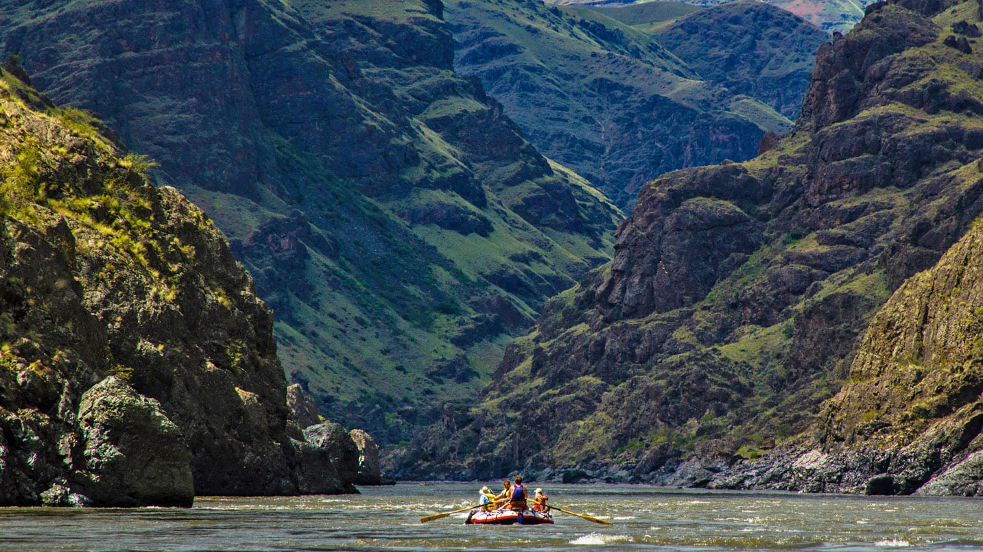 people on raft in middle of a deep canyon