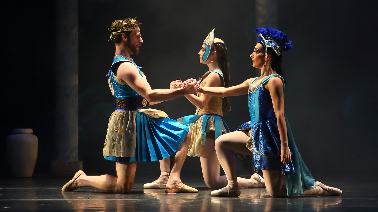 Ballet routine with two women and one man in Roman inspired costumes.