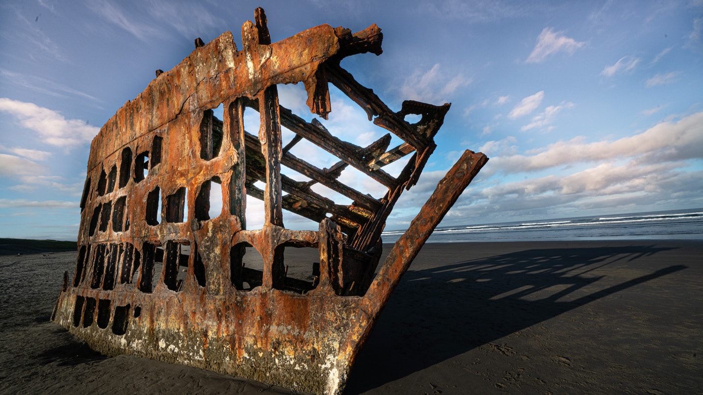 A rusted ship hull on the beach