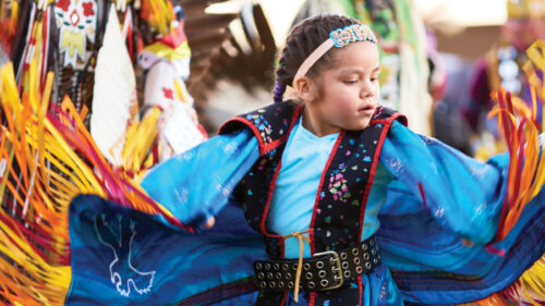 girl in colorful Native regalia dancing