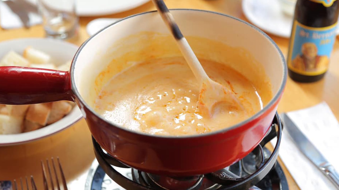 A pot of melted fondue cheese.
