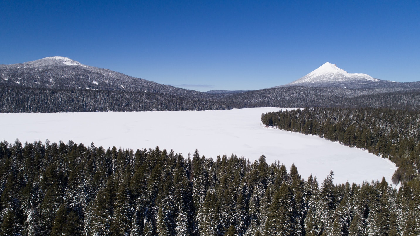 A snow covered lake and distant mountain peaks