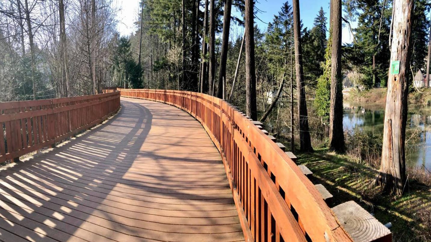 A wood plank bridge and path in a wooded area along a river in Tualatin.