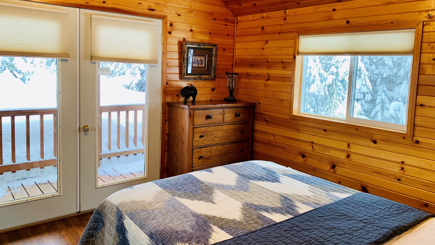View of a cabin bedroom with wood lined walls.