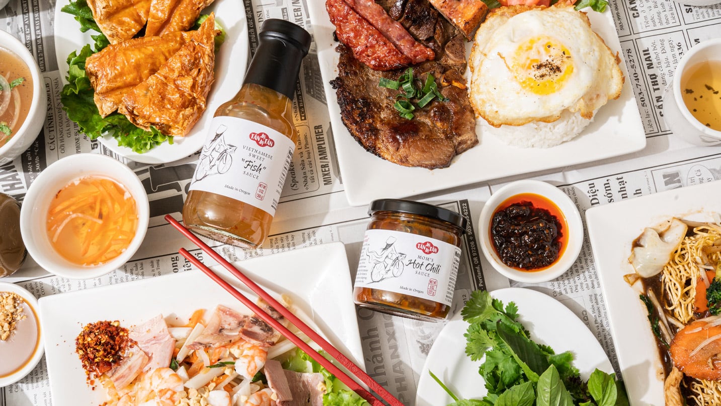 Plates of Vietnamese food and sauces displayed artfully as an overhead shot.