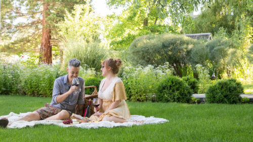 Two people having a good time outside on a picnic while sipping wine.