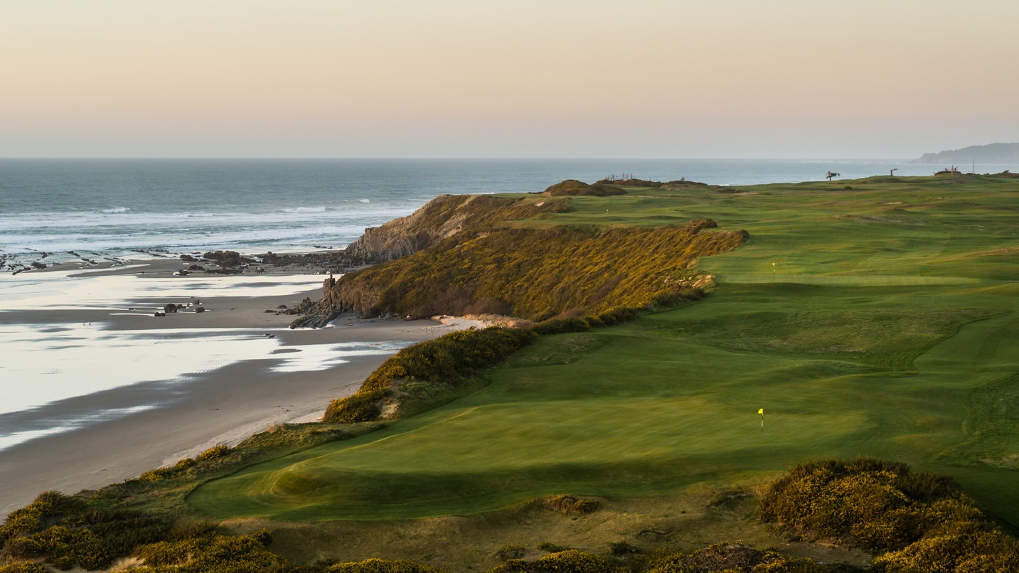 A landscape view of Sheep Ranch golf course overlooking a sandy area and the ocean.
