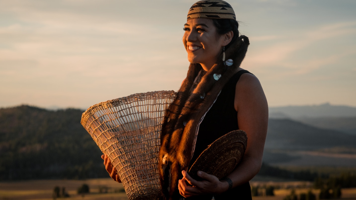 Woman in Native regalia holds basket