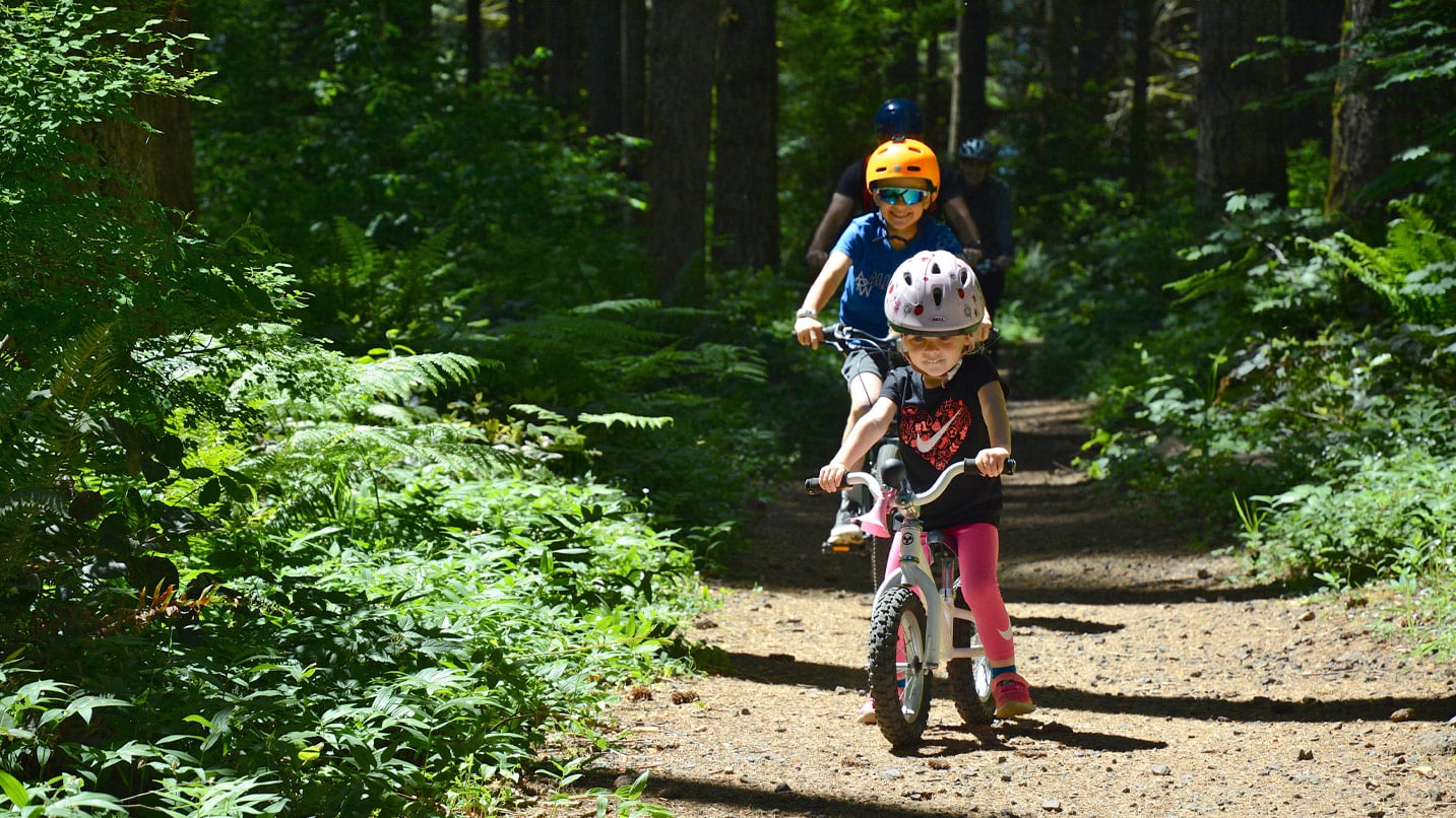 A toddler and child bike along a forest trail in Silver Falls.