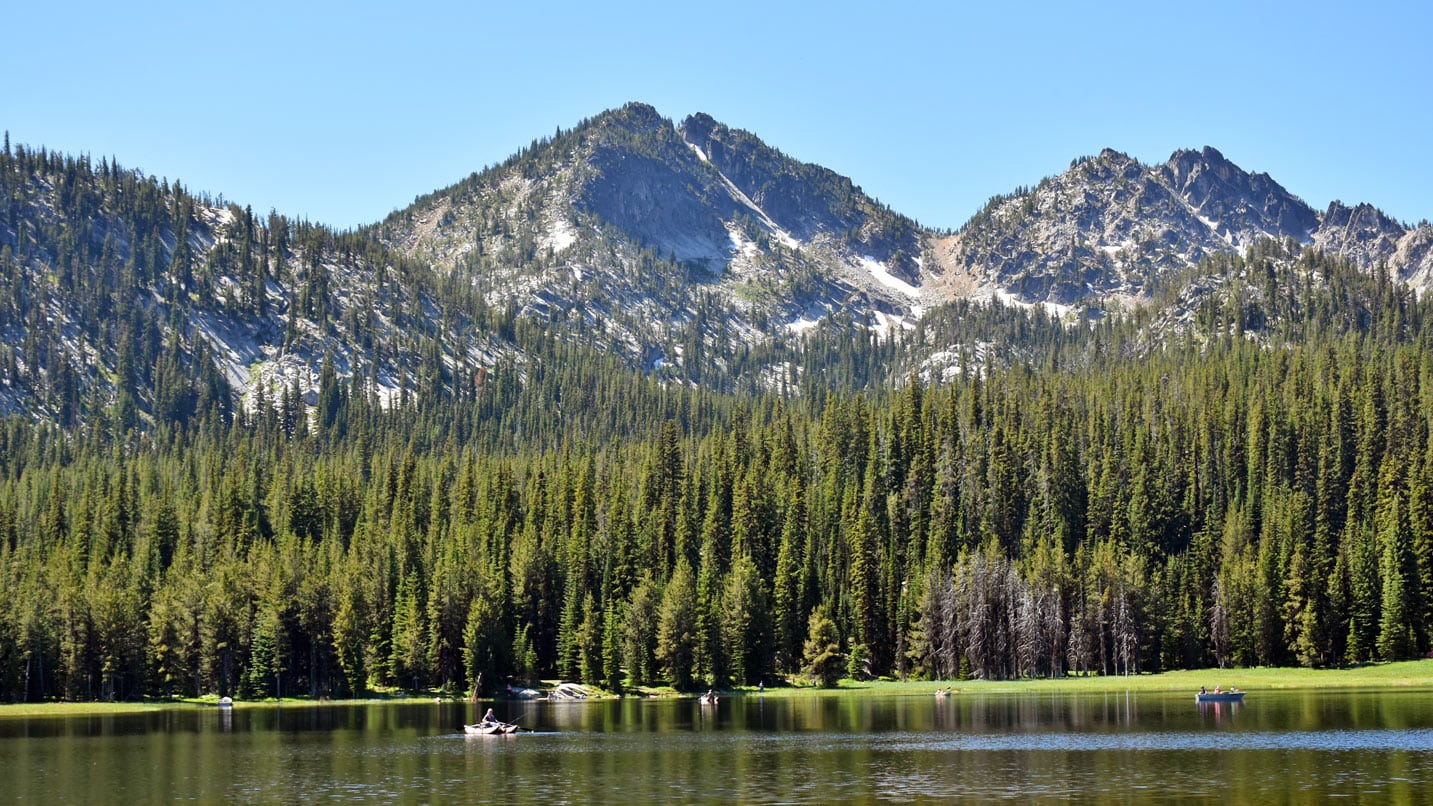 View of a mountain and surrounding lake with kayakers.