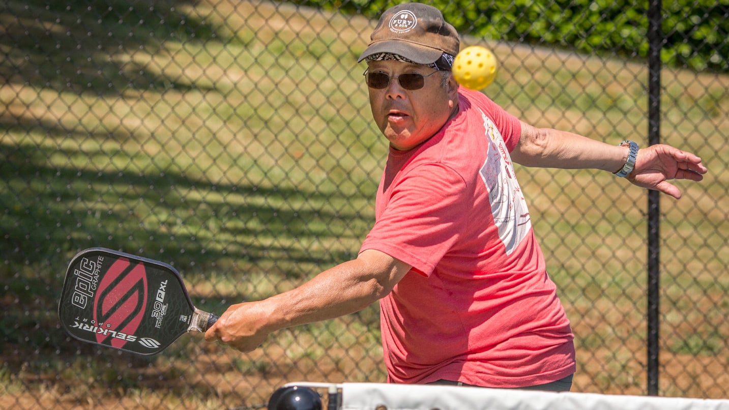 A man about to backhand an incoming pickleball.