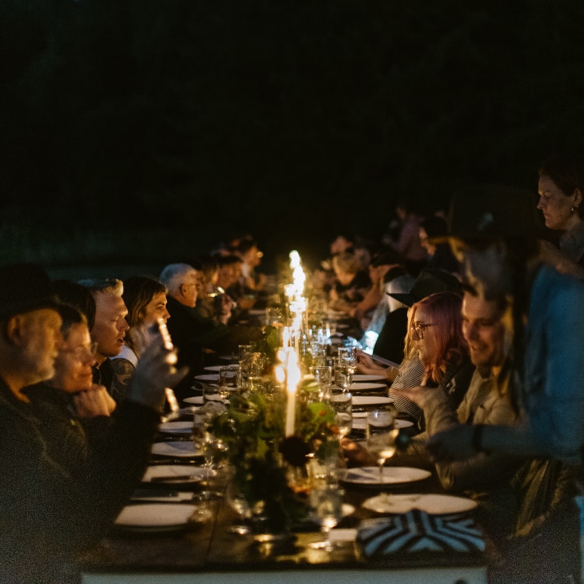 People sit at a long table lit by candlelight