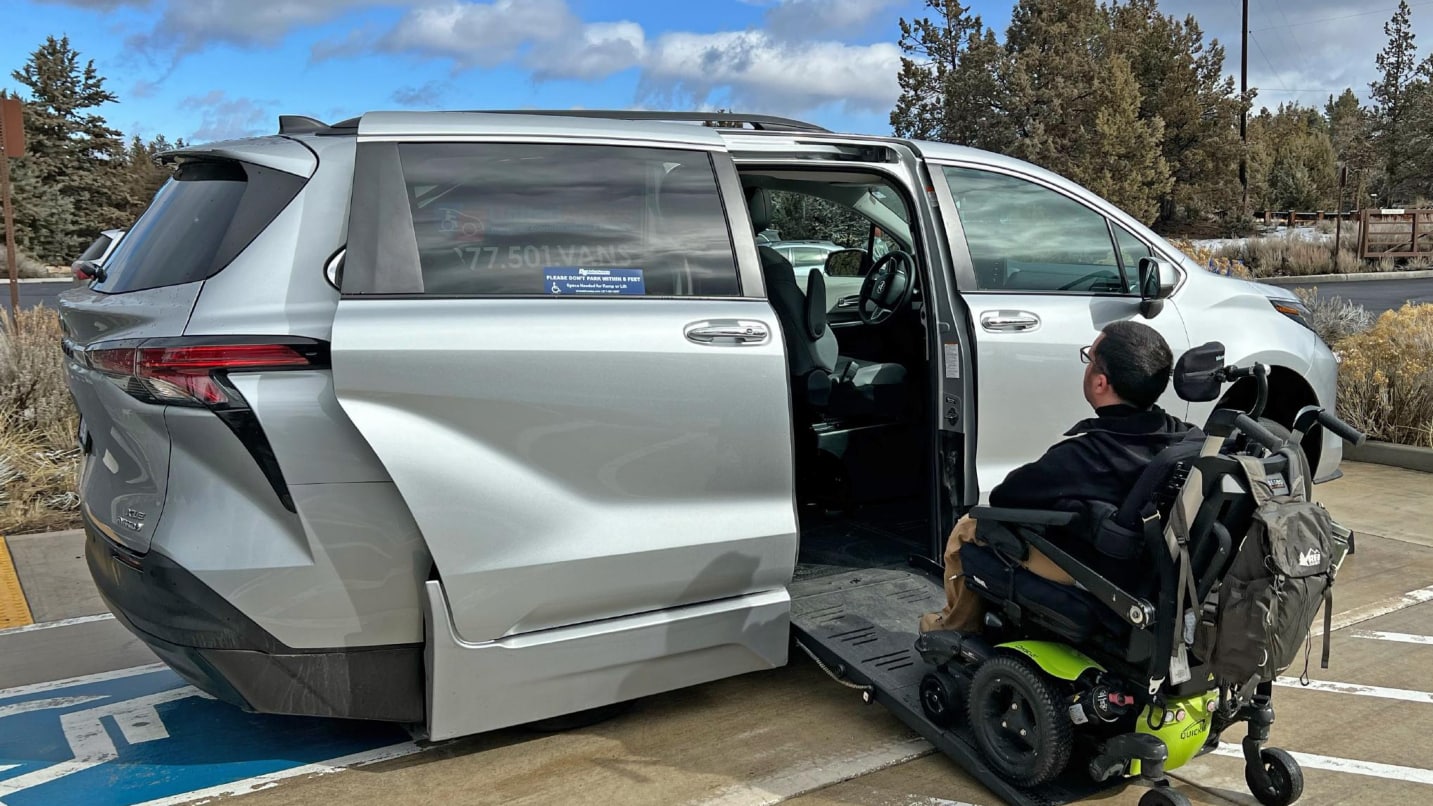 man in wheelchair goes up ramp into minivan