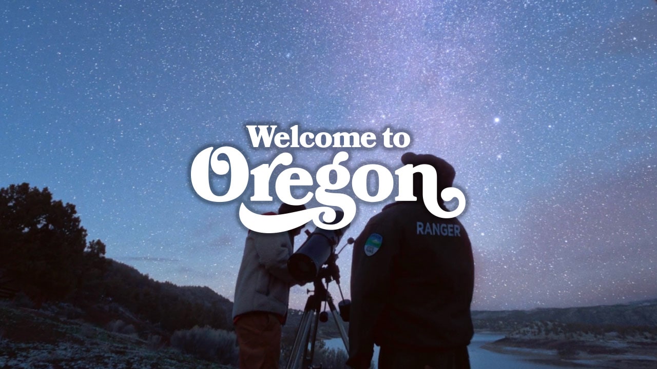 Two men looking up at stars in the sky. Text: Welcome to Oregon