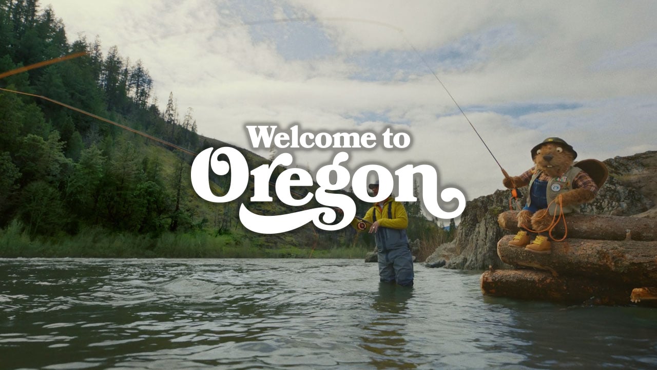 Man and puppet beaver fishing in a river. Text: Welcome to Oregon
