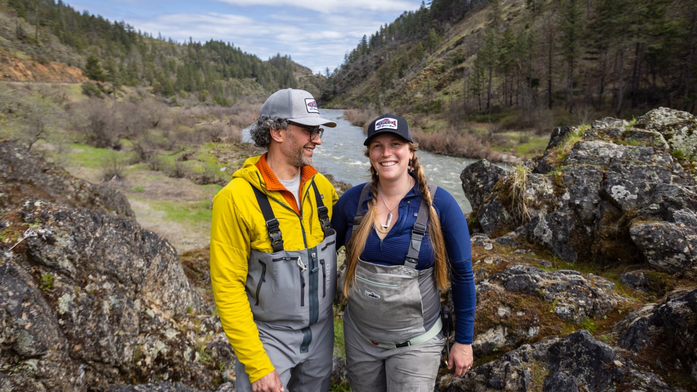 A couple pose for a portrait. The backdrop is the Rogue River