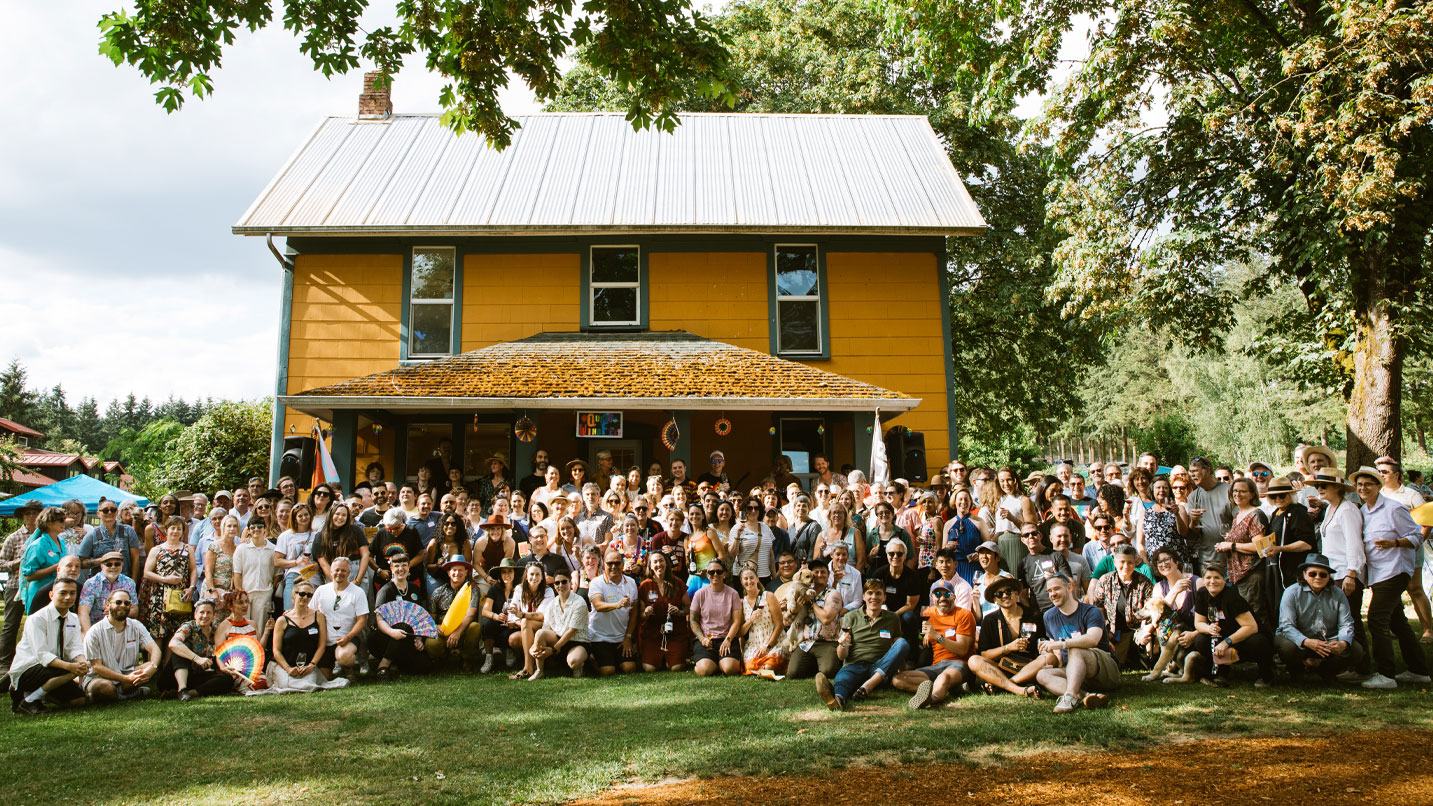 A group of people posing in front of a farm house.