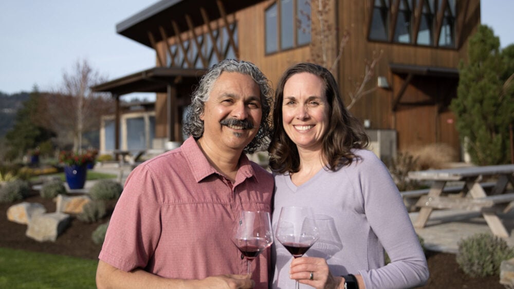 man and woman hold wine glasses smiling